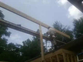 Carpenter setting a ridge beam over a new addition frame — Ice Dam Removal by Roofing Brothers in Mondamin