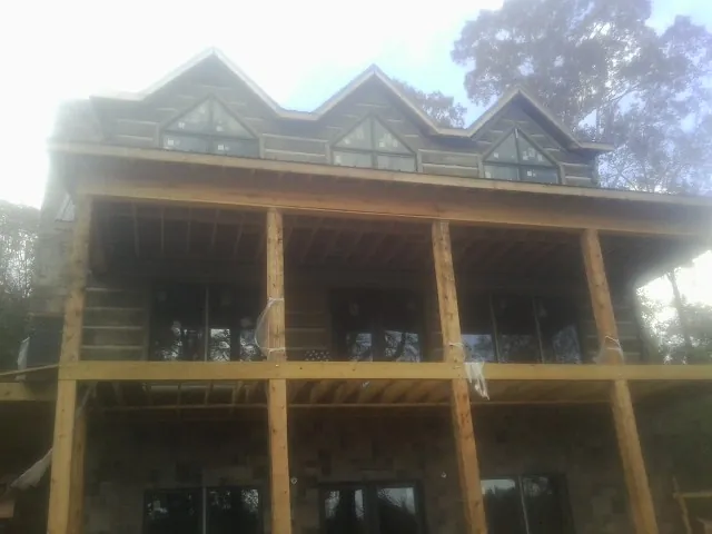 Dormers and porch framing on a large log home under construction — Roof Coating work by our crew in Mondamin