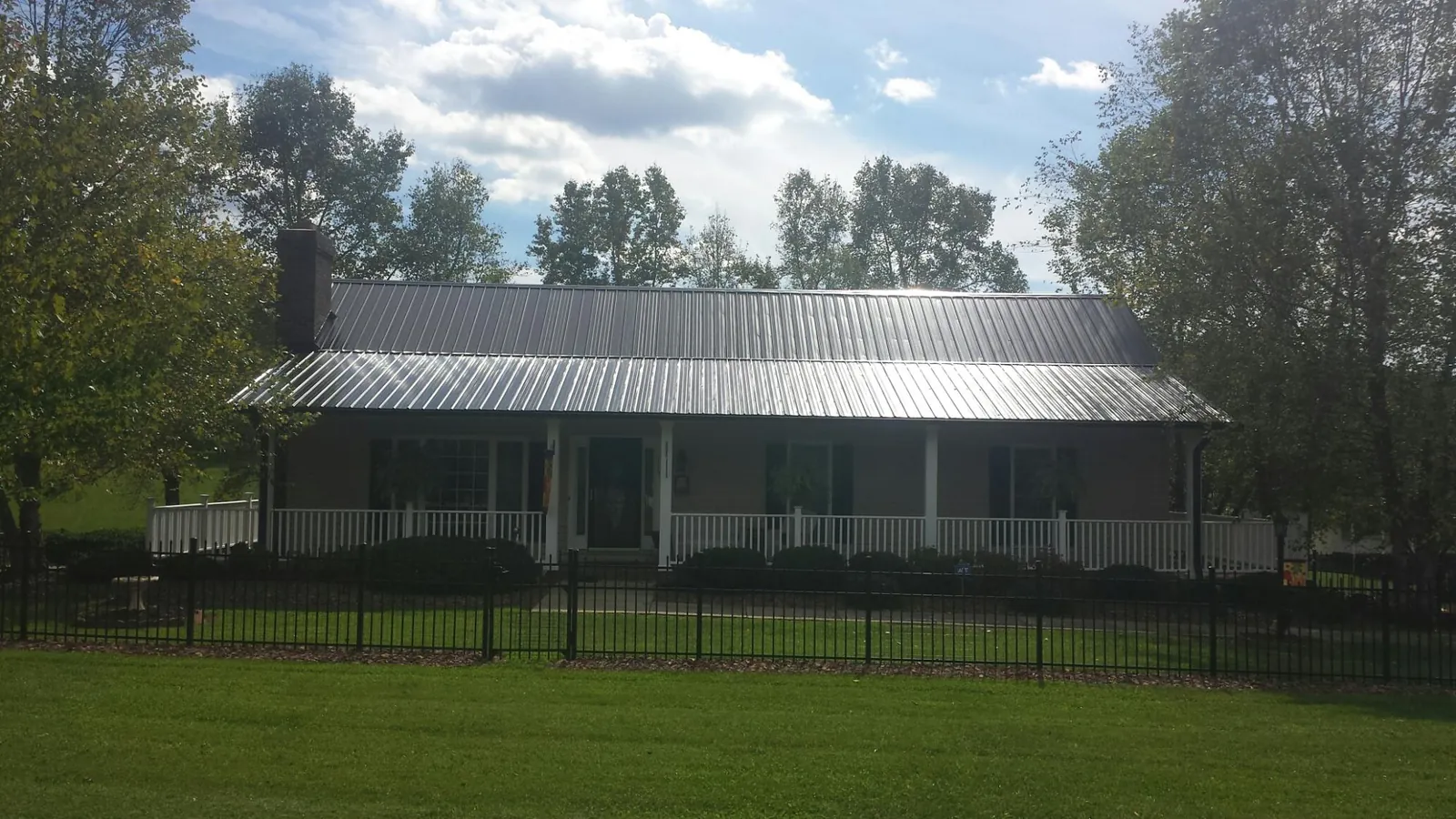 Gray metal roof on a brick ranch with a full width front porch — Gutter Guard Installation work by our crew in Mondamin