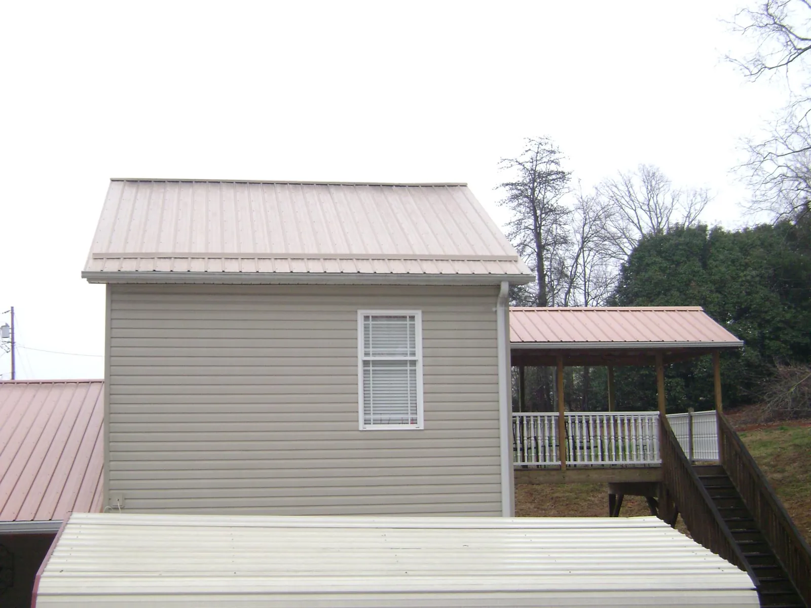 Tan metal roofs on a two story addition and attached porch, from a Roof Replacement job in Mondamin