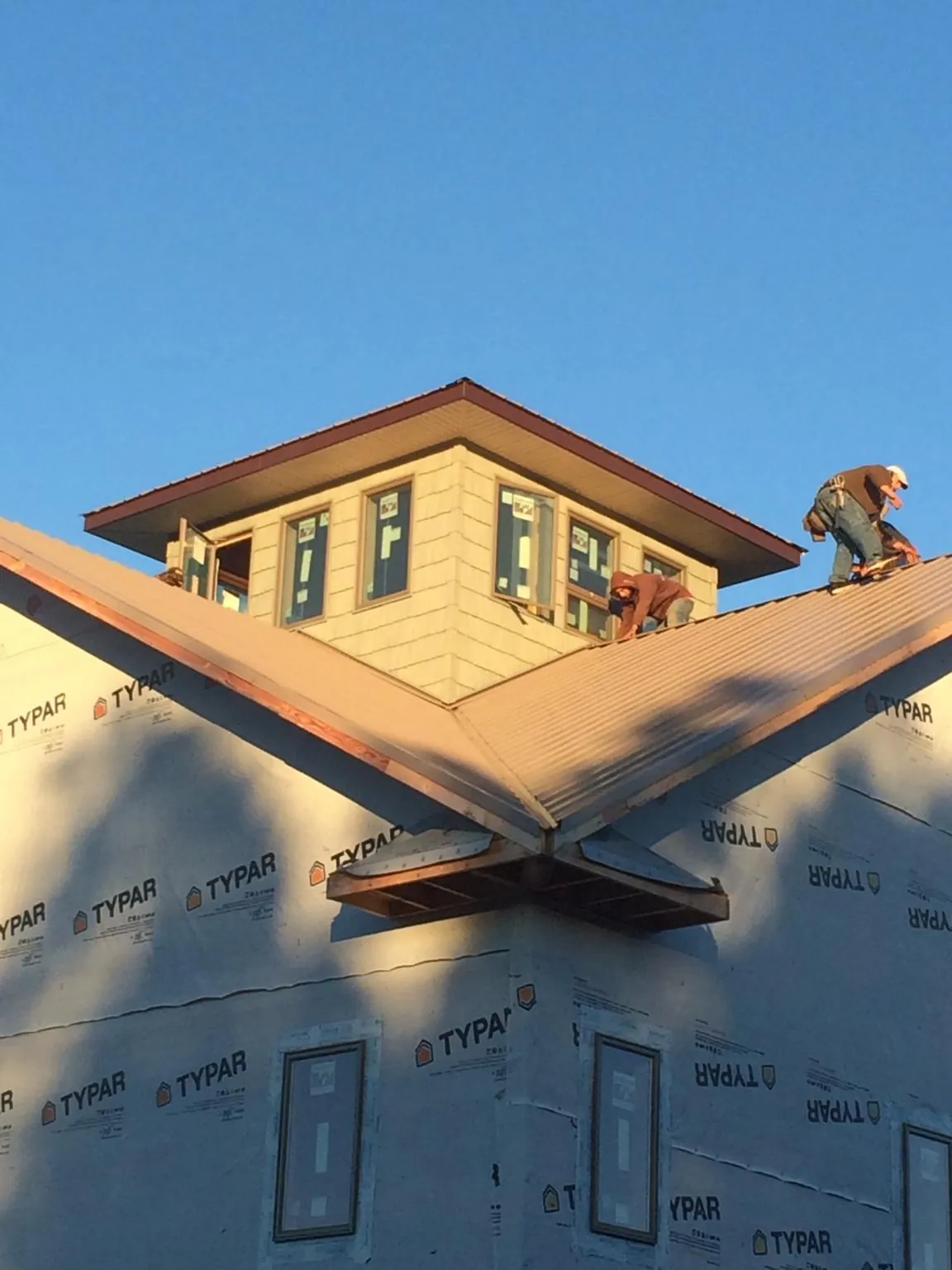 Roofers working around a rooftop cupola on a new metal roof at sunset — Roof Waterproofing in Mondamin by Roofing Brothers